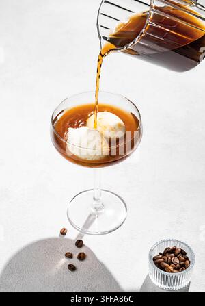Café affogato avec des boules de glace à la vanille et de l'espresso versé sur fond blanc avec des grains de café et de l'ombre. Concept classique de dessert italien f Banque D'Images