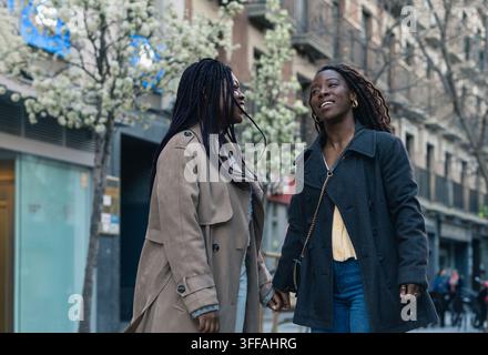 Deux femmes africaines heureuses se tenant la main et profitant d'une promenade en ville par une journée de printemps Banque D'Images