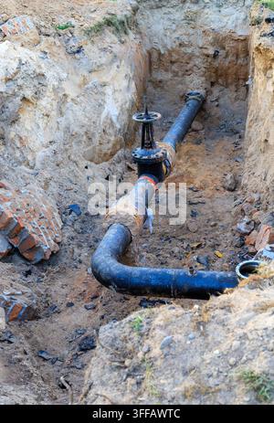 Tuyau souterrain d'utilité avec isolation thermique endommagée et vanne de contrôle dans une fosse de construction. Rénovation du système de chauffage, génie civil, un Banque D'Images