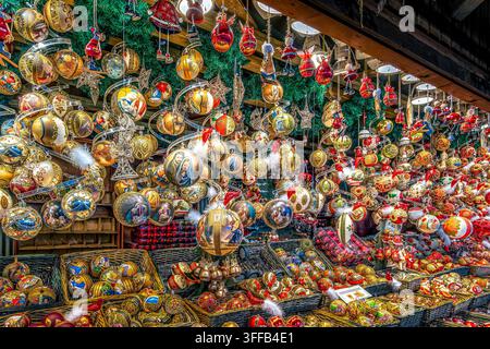 Ornements de verre traditionnels dorés et rouges pour sapin de Noël exposés dans des paniers et suspendus au plafond d'un étal de marché à Vienne, en Autriche. Banque D'Images