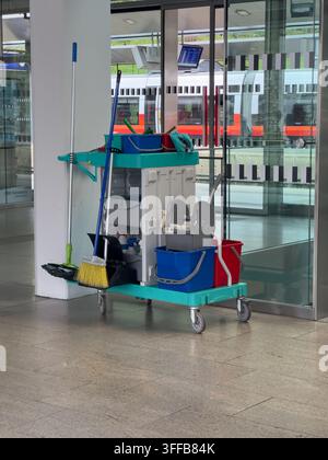 Chariot de nettoyage avec balais, seaux et supports de serpillières à l'intérieur d'une gare. Concept d'hygiène, de maintenance, de service et d'organisation et de soin du lieu de travail Banque D'Images
