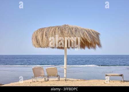 Parasol en paille et chaises longues sur une belle plage de sable. Banque D'Images