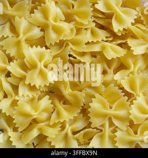 Gros plan de pâtes Farfalle sèches, fond en texture alimentaire avec des pâtes italiennes en forme d'arc Banque D'Images