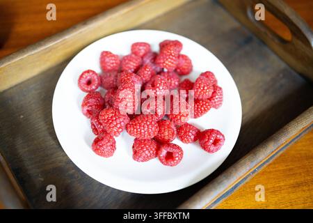 Fraises rouges fraîches et mûres sur une assiette blanche dans un plateau en bois rustique Banque D'Images