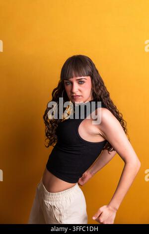 Jeune femme posant avec assurance sur un fond jaune Banque D'Images