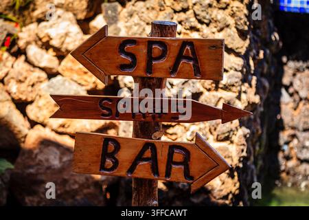 Un panneau en bois avec des panneaux en forme de flèche indique le chemin vers le spa, le spa #5 et le bar. Banque D'Images