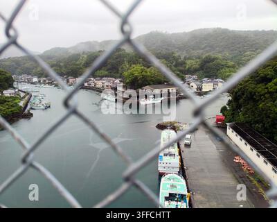 Une vue pittoresque à travers une clôture en grillage sur des bateaux de pêche à Toyo, Kochi, Japon en juillet 2026. Banque D'Images