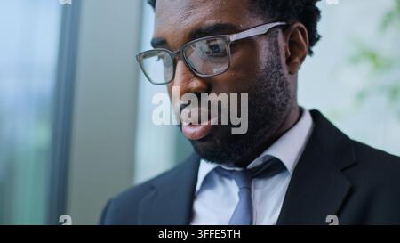 C;pse visage levé d'un homme d'affaires afro-américain malheureux, pensif et sérieux portant des lunettes, regardant vers le bas et réfléchissant au bureau, homme d'affaires inquiet et pensif Banque D'Images
