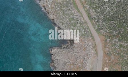 Perspective aérienne d'une côte rocheuse en Crète, présentant une route sinueuse adjacente à la mer turquoise, avec des eaux claires et des formations rocheuses visibles Banque D'Images