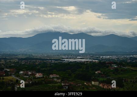Vue panoramique de la ville, toits rouges, champs et fond de montagnes brumeuses Banque D'Images