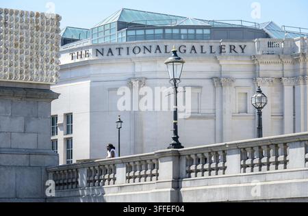 Londres, Royaume-Uni. Trafalgar Square - touriste regardant la place depuis l’avant de la Sainsbury Wing de la National Gallery Banque D'Images