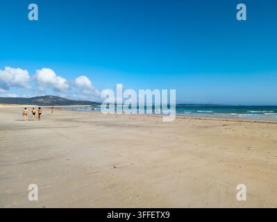 Des gens marchant sur une plage de sable à marée basse sur la côte atlantique à Corrubedo, Galice, Espagne Banque D'Images
