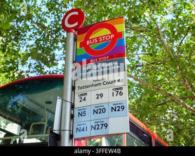 Arrêt de bus décoré du drapeau arc-en-ciel de la fierté gaie autour du panneau rond TFL à Traflagar Square, Londres, Royaume-Uni Banque D'Images