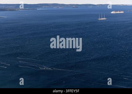 Une vue matinale pittoresque sur le golfe de Trieste avec des yachts de luxe et une vedette de passagers naviguant à travers la mer bleue et calme sous une lumière douce. Banque D'Images