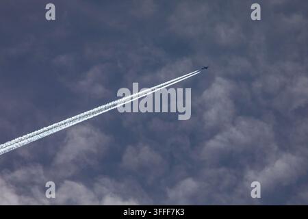 Un avion créant une traînée de vapeur sur la traînée de condensation dans le ciel. Banque D'Images