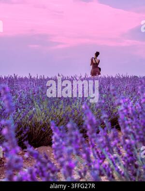 Vue arrière d'une jeune femme adulte debout dans un champ de lavande tout en prenant une photo Banque D'Images
