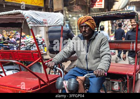 Conducteur de rickshaw à vélo debout à côté de rickshaws dans une rue de New Delhi, en Inde. Banque D'Images