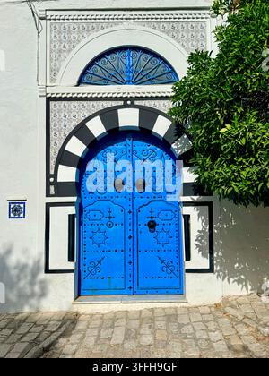 Porte ornée de clous bleus avec des carreaux décoratifs sur une maison traditionnelle blanchie à la chaux à Sidi Bou Said, Tunis, Tunisie Banque D'Images