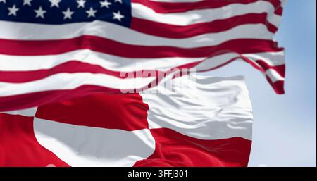 Drapeaux du Groenland et des États-Unis agitant au vent par temps clair. Le Groenland est la plus grande île du monde. rendu d'illustration 3d. Tissu ondulé. Mise au point sélective - photomontage Banque D'Images