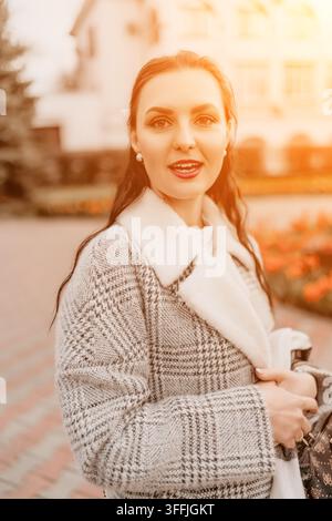 Femme mode coucher de soleil dame élégante en manteau de laine posant dans un parc automnal pendant l'heure dorée avec une atmosphère de style de vie chaleureuse Banque D'Images