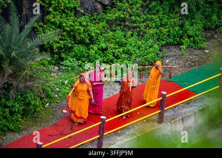 Des femmes indiennes portant un Kavad traditionnel sur leurs épaules lors d'un pèlerinage religieux, marchant dans une rue dans le cadre d'un voyage dévotionnel. Banque D'Images
