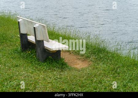 Banc en béton vide face à une eau calme Banque D'Images