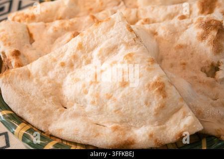 Close-up de tranches de pain naan indien fraîchement cuit, servi sur une assiette tissée. Banque D'Images