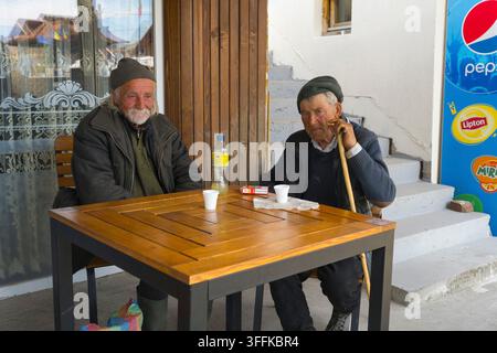 Deux hommes âgés ayant une conversation détendue et buvant de la limonade à une table extérieure, Sapanta, Sapanta, Maramures, Maramures, Maramuresh, Roumanie Banque D'Images
