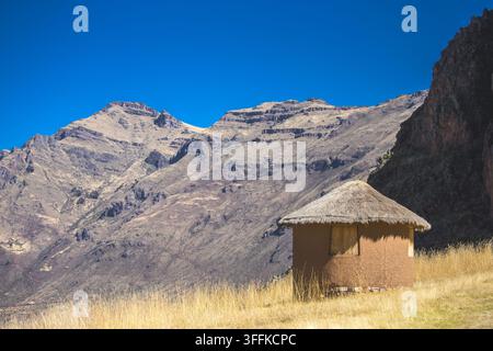 Vue d'une hutte ronde traditionnelle au toit de chaume située dans le paysage montagneux de la Vallée Sacrée de la province d'Urubamba, Cusco, Pérou. Banque D'Images