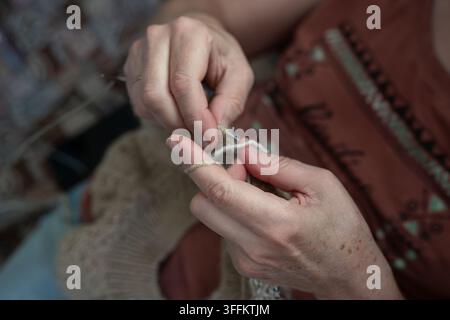 Femme tricotant un vêtement en laine fait main avec des aiguilles à tricoter Banque D'Images