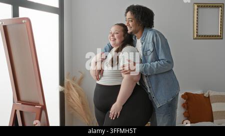 Femme de taille plus embrassée par derrière par l'homme avec la main sur l'épaule, debout par miroir dans le studio ; l'affection d'acceptation d'intimité. Banque D'Images