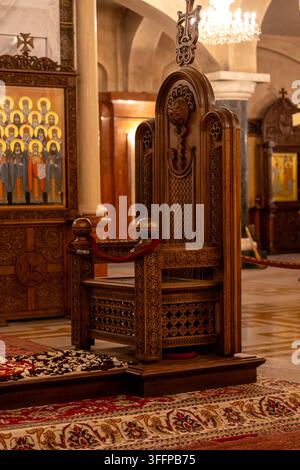 Un trône en bois richement décoré, présentant des sculptures détaillées et une croix proéminente, se dresse dans un cadre sacré d'église. Cathédrale de la Sainte Trinité, Sa Banque D'Images