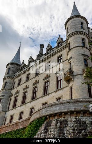 Ancien château de pierre avec des tourelles pointues et des fenêtres encadrées de rouge sous un ciel nuageux à Dunrobin Castle, Écosse, Royaume-Uni. Banque D'Images