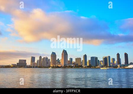 La ligne d'horizon de San Diego est illuminée par la lumière dorée de l'heure dorée alors que des nuages dérivent au-dessus de la ville. La baie de San Diego reflète les tours du centre-ville et le scèn Banque D'Images
