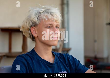 Une jeune femme blonde est assise à l'intérieur et regarde calmement sur le côté. Banque D'Images