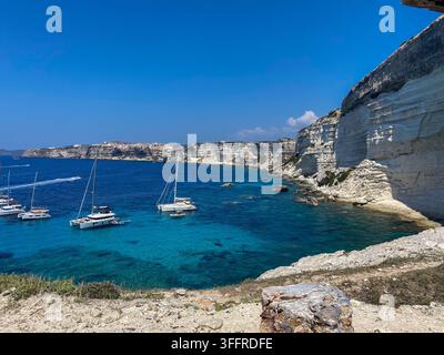 Vue panoramique en hauteur de catamarans de luxe et de voiliers ancrés dans une mer turquoise cristalline. La baie immaculée est entourée du dramatique, Banque D'Images