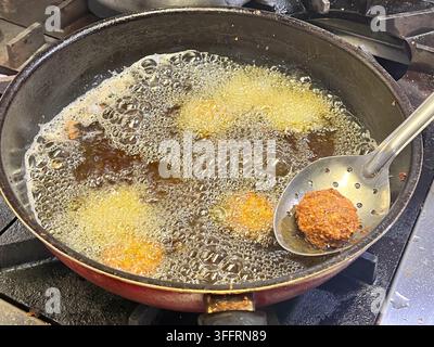 Boulettes de falafel frites dans une poêle à frire. Le falafel est une boule ou une galette frite d'origine égyptienne, dans une cuisine. Banque D'Images