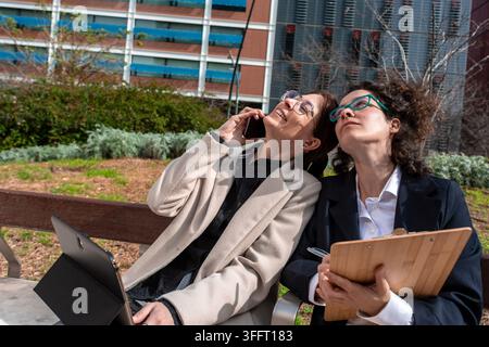 Femmes d'affaires collaborant en plein air avec une tablette et un smartphone Banque D'Images