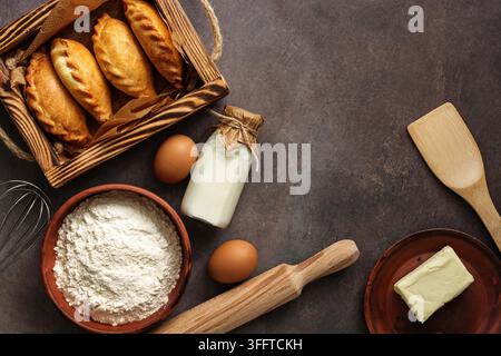 Fond de cuisson, ingrédients pour faire des tartes, farine, beurre, lait, œufs. Les Russes traditionnels ont cuit des pâtés pirozhki Banque D'Images