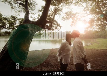 Un moment tendre et romantique capturé au coucher du soleil dans un parc luxuriant et naturel en Indonésie Banque D'Images