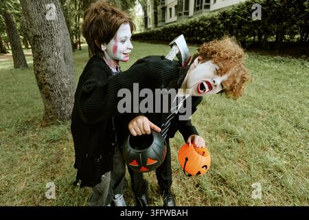 Garçons portant des costumes d'Halloween effrayants jouant à l'extérieur dans un parc Banque D'Images