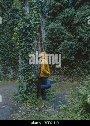 Un jeune homme dans un imperméable jaune, au milieu du lierre dans le bâtiment abandonné. Banque D'Images