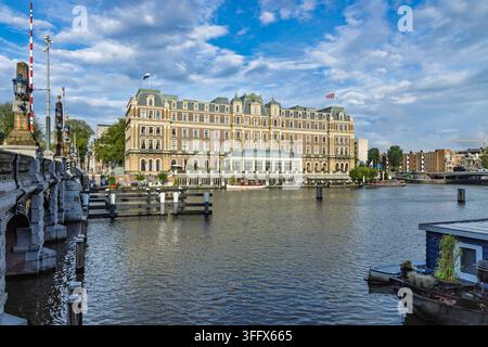 Amsterdam, Pays-Bas : Vue en perspective du célèbre hôtel Amstel et du pont Hogesluis sur l’Amstel, avec des péniches classiques et bleu Banque D'Images