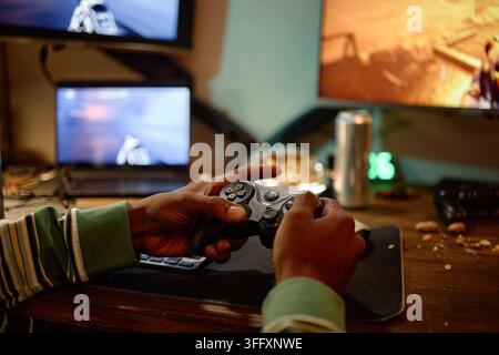 Homme noir tenant une manette de jeu et jouant à des jeux vidéo à la maison Banque D'Images