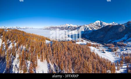 Vue aérienne automnale de la vallée de Champsaur dans les Alpes françaises, avec une forêt de mélèzes dorés et des montagnes enneigées. Ancelle, Hautes-Alpes, France Banque D'Images