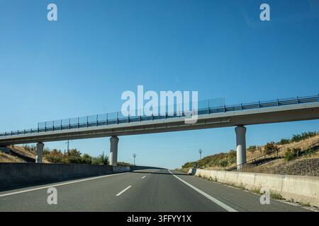 Autoroute déserte sous un viaduc en béton par une journée ensoleillée Banque D'Images