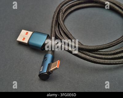 Câble de charge tressé USB-C vers USB-A – Gros plan d’un câble de charge et de données tressé noir USB-C vers USB-A avec connecteurs bleu-vert, indiquant une puissance de 100 W Banque D'Images