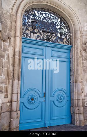 Un gros plan détaillé d'une grande porte double en bois bleu ornée, encadrée dans une arche en pierre avec des ferronneries décoratives à Lille, en France. Banque D'Images