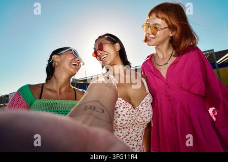 Différentes amies femmes prenant un selfie, riant et profitant du temps ensemble sous un ciel d'été ensoleillé. Bonheur et lien Banque D'Images