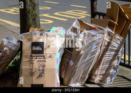 Des piles de déchets de carton commerciaux de Biffa sont empilées sur le trottoir près d'un arrêt de bus dans une rue publique. Southport, Royaume-Uni. Banque D'Images